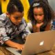 two kids using laptop